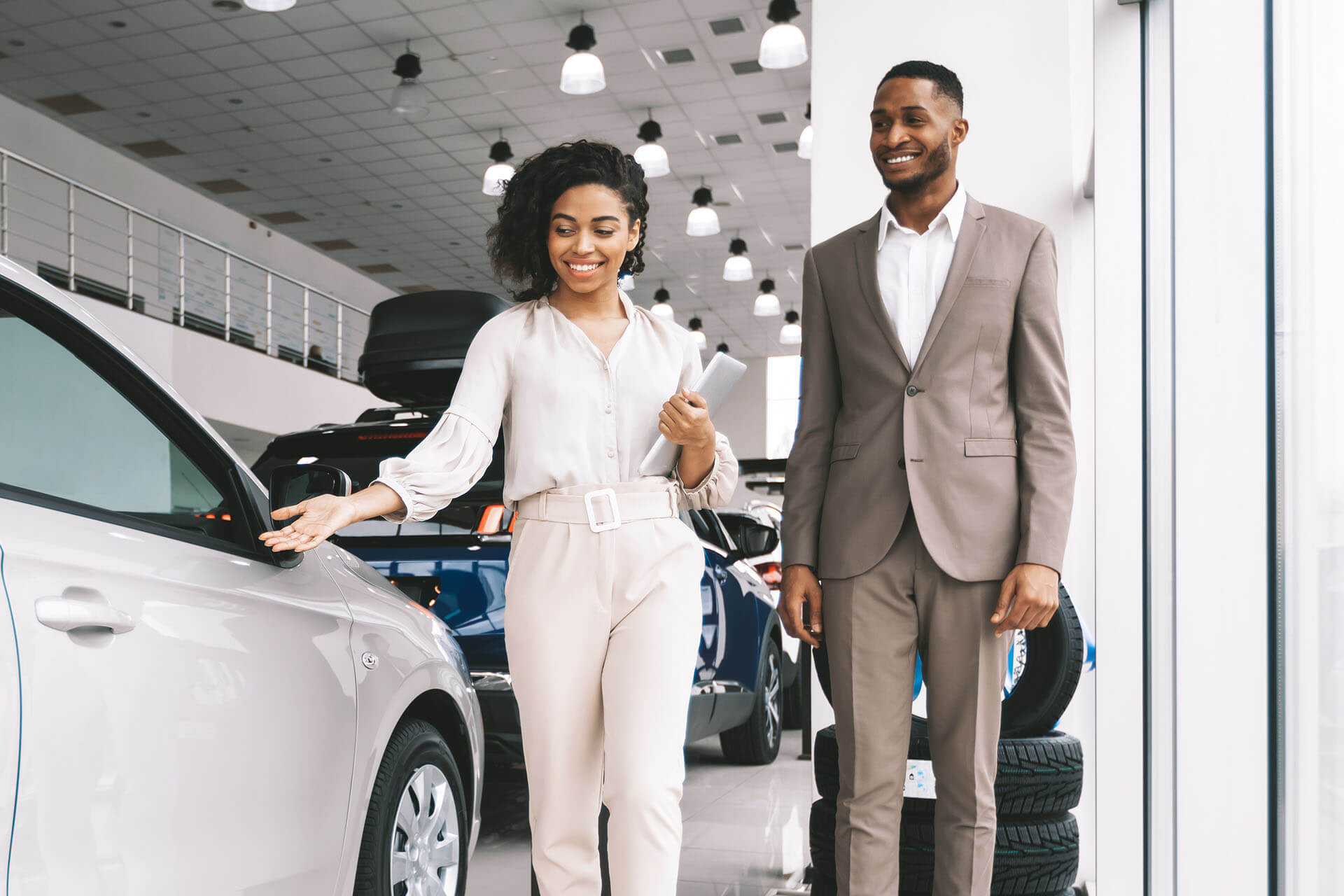 Saleswoman showing a car to a man inside a car dealership