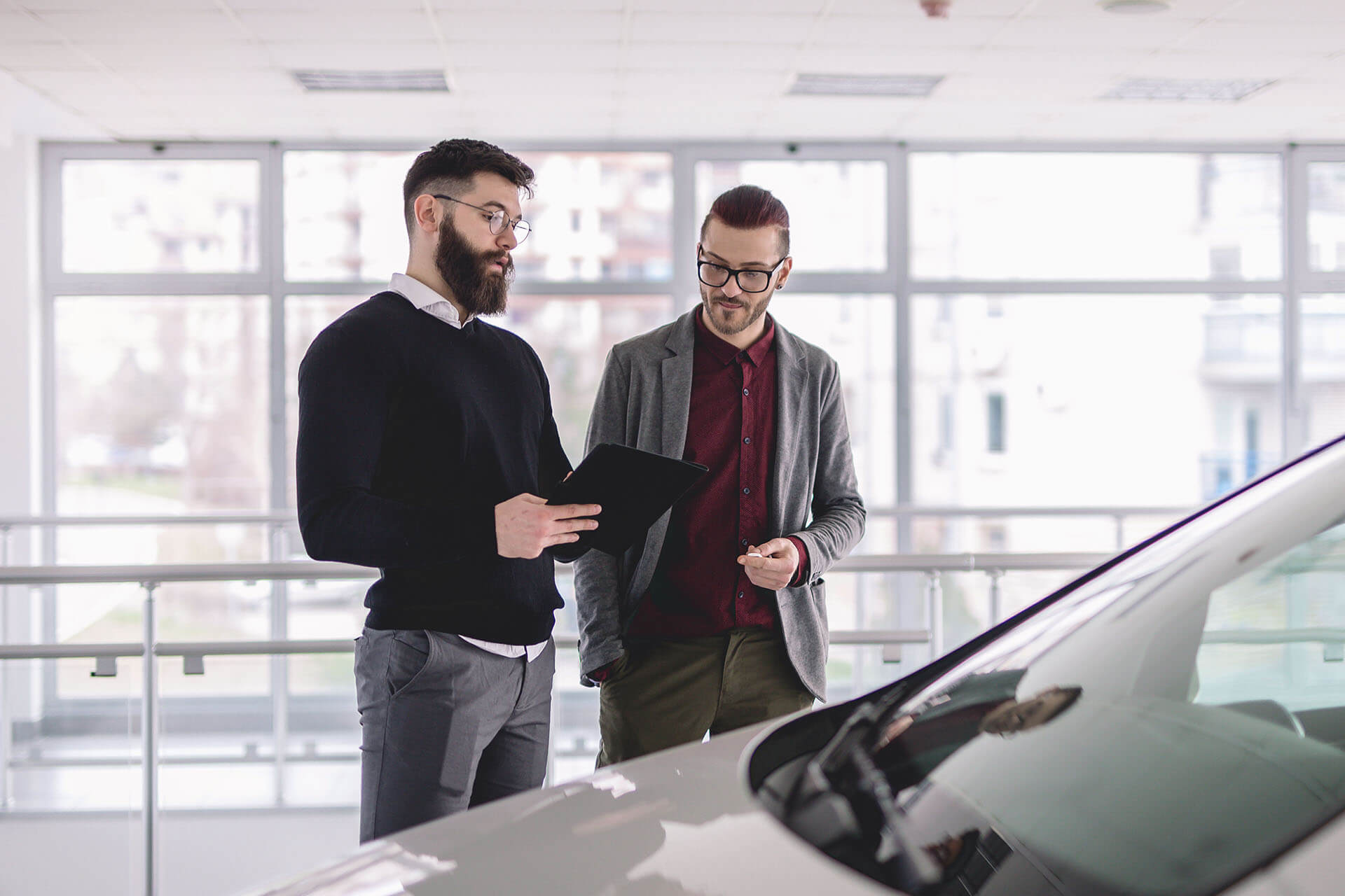 Two men looking at tablet in car dealership