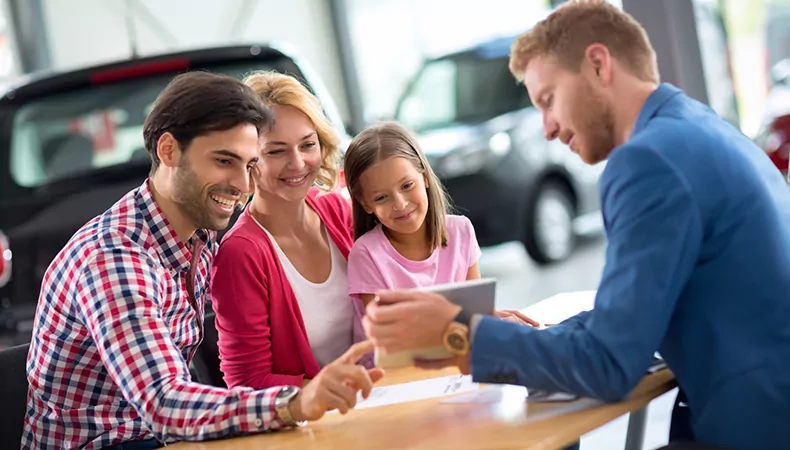 Happy family in car dealership choosing their new car